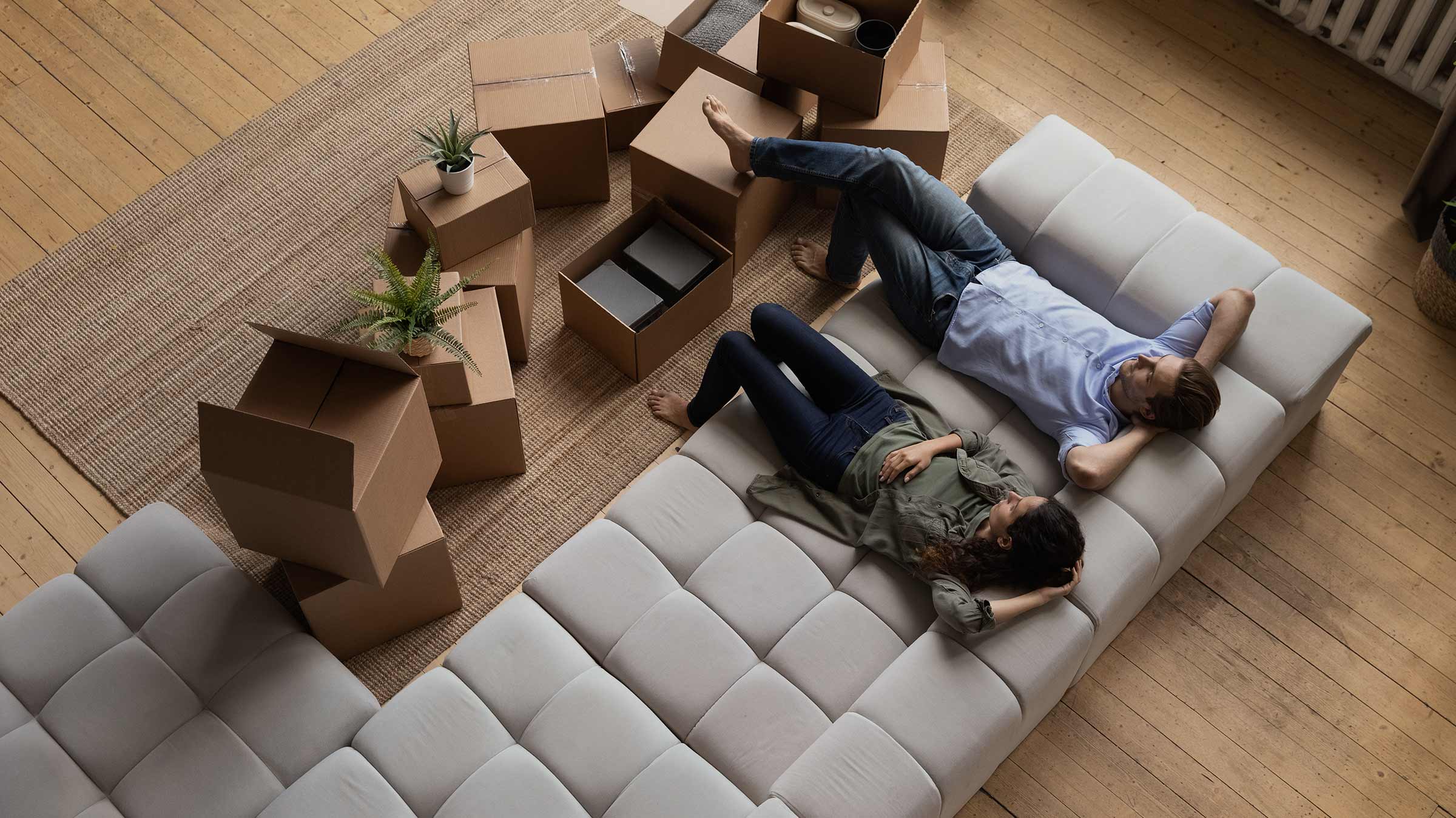 Couple relaxing on couch surrounded by moving boxes