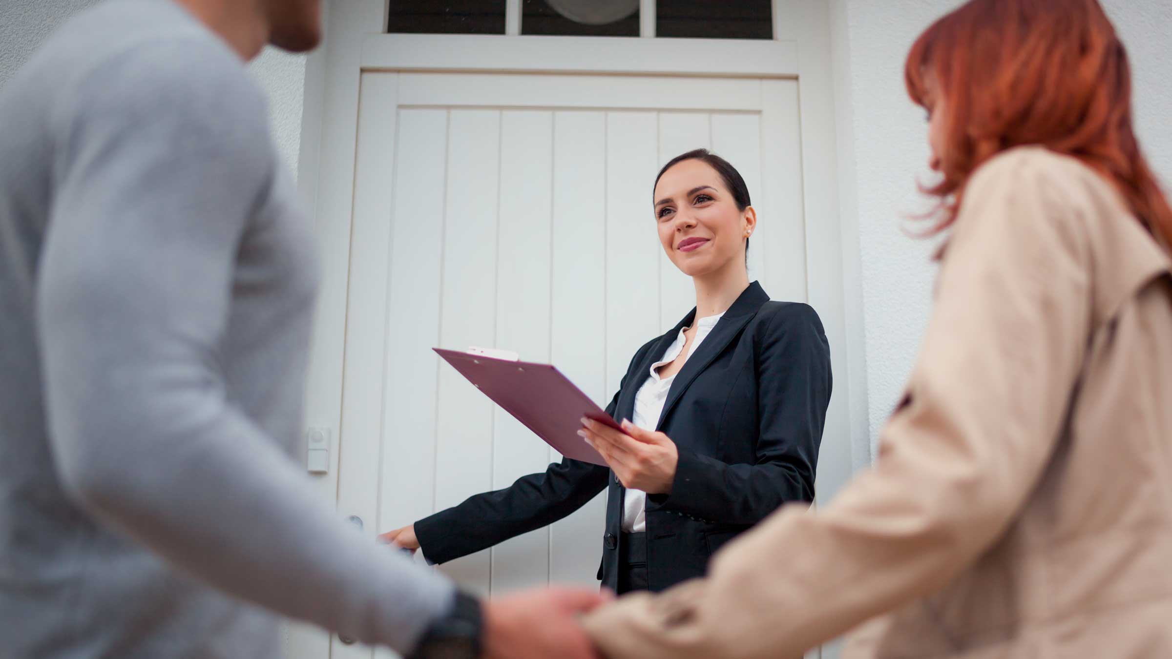 Real Estate Agent opening door for couple to view house